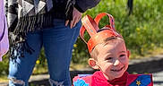 Evan participe au concours pour gagner de l'argent avec cette photo : child, costume, crown, red_clothing, outdoor, sunlight, smiling, adult, jeans, scarf, casual_clothing, celebration, happy, person, daylight, nature, greenery, photography, playful, event
