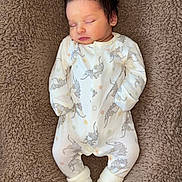 Valerio participe au concours pour gagner de l'argent avec cette photo : baby, newborn, sleeping, onesie, elephant_print, white_clothing, socks, blanket, brown, soft_texture, infant, peaceful, portrait, cute, resting, indoors, small_child, child, person, cozy