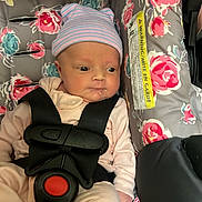 Charlee is registered to the contest to win money with this photo: baby, infant, car_seat, floral_pattern, hat, drool, stripes, clothing, seat_belt, safety_harness, pink, blue, newborn, cute, child, person, indoors, soft_lighting, fabric, pattern