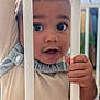 Elyot participe au concours pour gagner de l'argent avec cette photo : baby, child, face, hand, crib, bars, curious, indoors, nursery, toy, soft_lighting, closeup, expression, clothing, person, infant, young_child, skin, portrait, candid