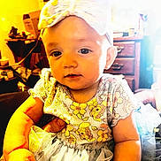 Oakley is registered to the contest to win money with this photo: baby, child, headband, bow, tutu, dress, floral_pattern, indoor, furniture, drawer, hand, person, cute, infant, smiling, portrait, holding, soft_lighting, tulle, young_child