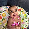 baby, child, infant, portrait, smiling, happy, sitting, indoors, couch, cushion, floral, colorful, pink_outfit, blue_couch, brown_hair, big_eyes, looking_at_camera, close_up, cozy, photography