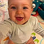 baby, infant, smiling, close_up, face, blue_eyes, eyelashes, chubby_cheeks, open_mouth, onesie, play_mat, toy, plush, sitting, hands, legs, home_interior, cozy, joyful, candid