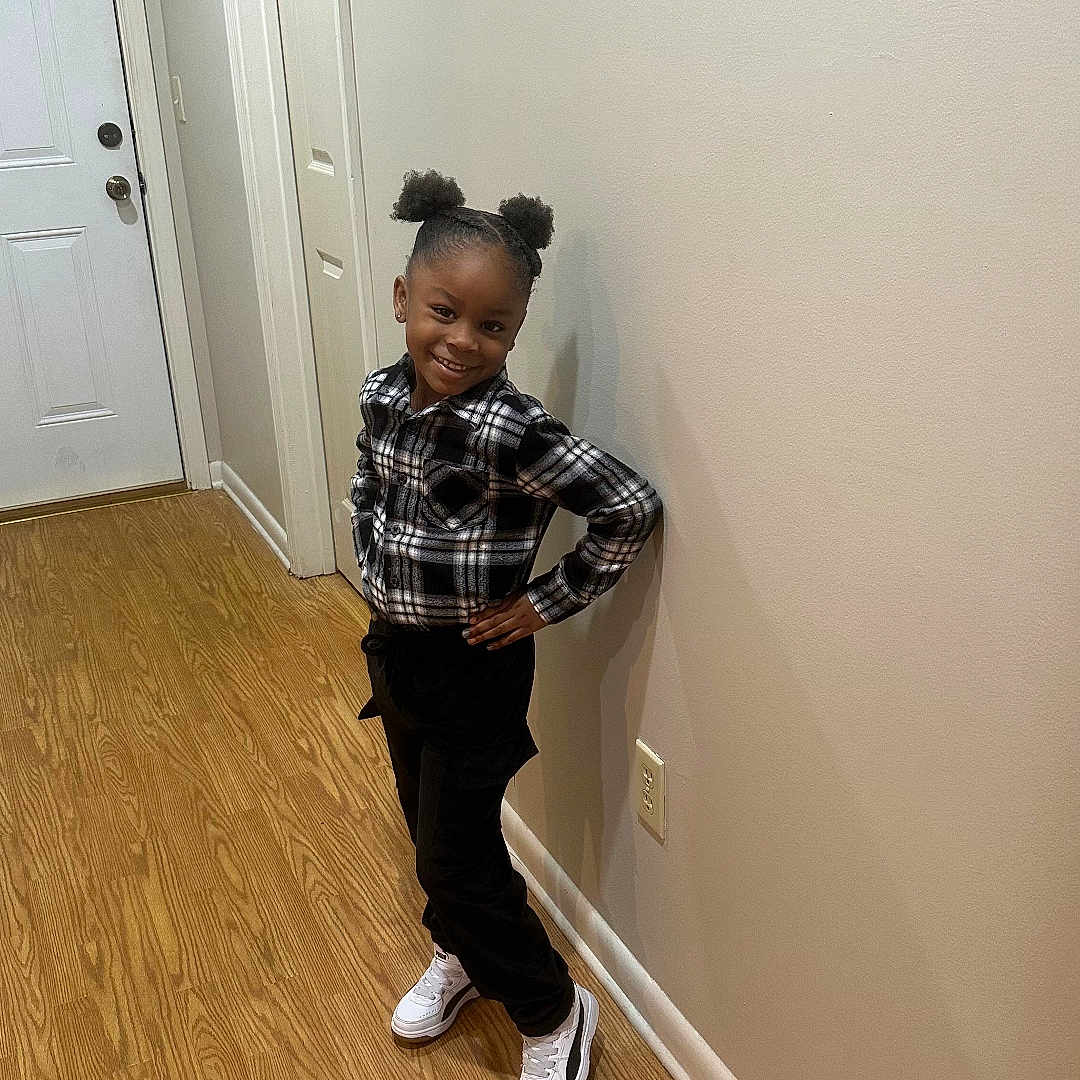 Amaree is registered to the contest to win money with this photo: blackhair, boy, child, clothing, face, footwear, hair, hardwood, head, indoors, interiordesign, jeans, male, pants, person, shoe, sitting, sleeve, standing, wood