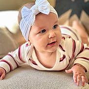 Eloah is registered to the contest to win money with this photo: baby, child, headband, bow, blue_eyes, striped_clothing, couch, texture, indoor, person, portrait, cute, infant, closeup, soft_light, smiling, hand, face, young_child, curious
