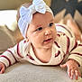 baby, child, headband, bow, blue_eyes, striped_clothing, couch, texture, indoor, person, portrait, cute, infant, closeup, soft_light, smiling, hand, face, young_child, curious