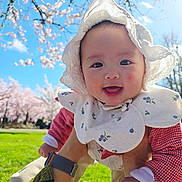 Alina joined the competition — help win amazing prizes! baby, infant, smiling, sun_hat, lace_hat, bib, outdoor, cherry_blossom, spring, grass, park, blue_sky, holding_hands, happy, portrait, face, cheeks, sunlight, playtime, cute