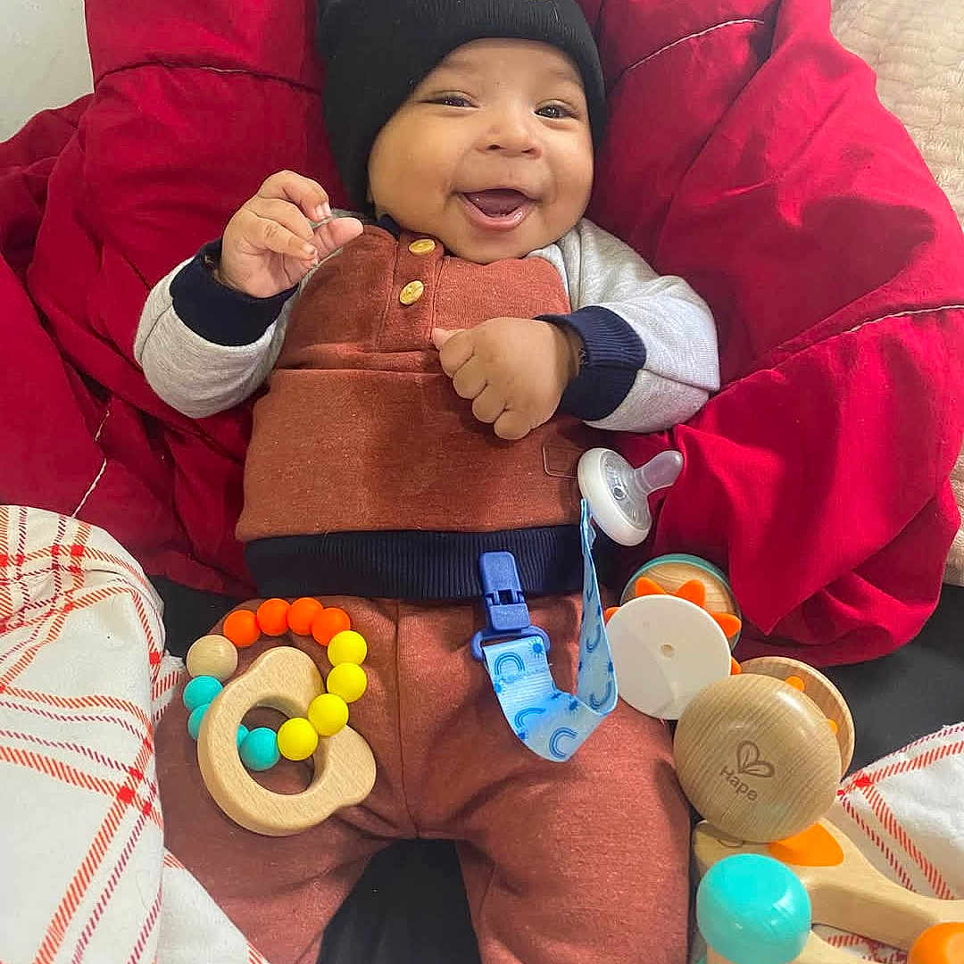 Malachi is registered to the contest to win money with this photo: baby, babylaughing, beanbag, blanket, face, furniture, happy, head, person, photography, portrait, smile, tape, toy