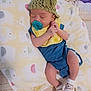 baby, newborn, sleeping, pacifier, hat, knitted_hat, bib, yellow_bib, blue_outfit, sock, animal_sock, blanket, elephant_pattern, soft_blanket, infant, cute, cozy, indoor, resting, child