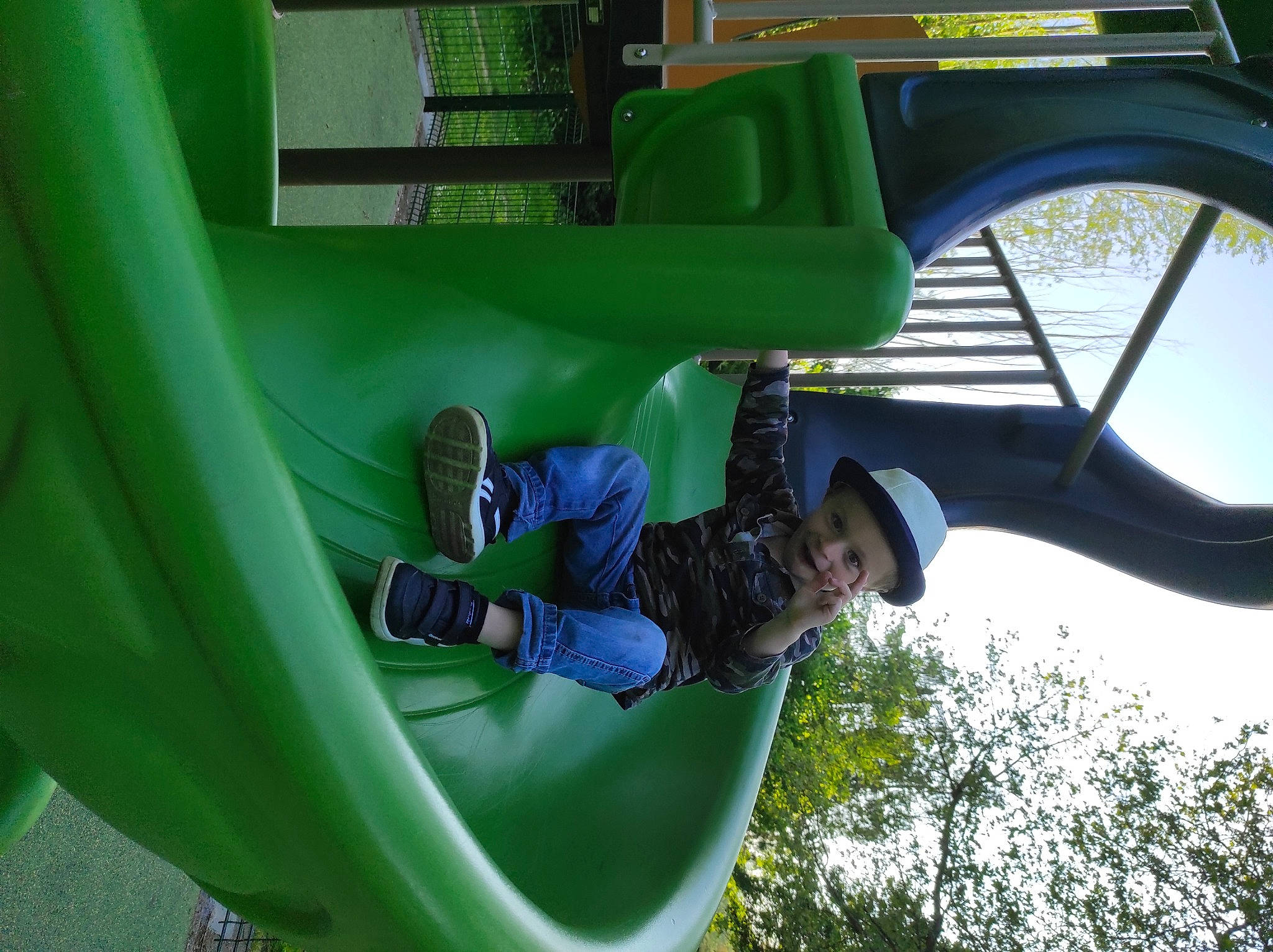 Timmy participe au concours pour gagner de l'argent avec cette photo : automotive_exterior, automotive_tire, automotive_wheel_system, chute, city, fun, grass, green, hat, headwear, leaf, leisure, outdoor_play_equipment, person, plant, playground, playground_slide, recreation, t_shirt, transport