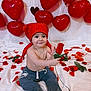 baby, balloons, barefoot, big_eyes, bracelet, celebration, child, heart_balloons, infant, jeans, necklace, red_bandana, red_color, rose, rose_petals, sitting, smile, studio_shot, valentine_theme, white_backdrop