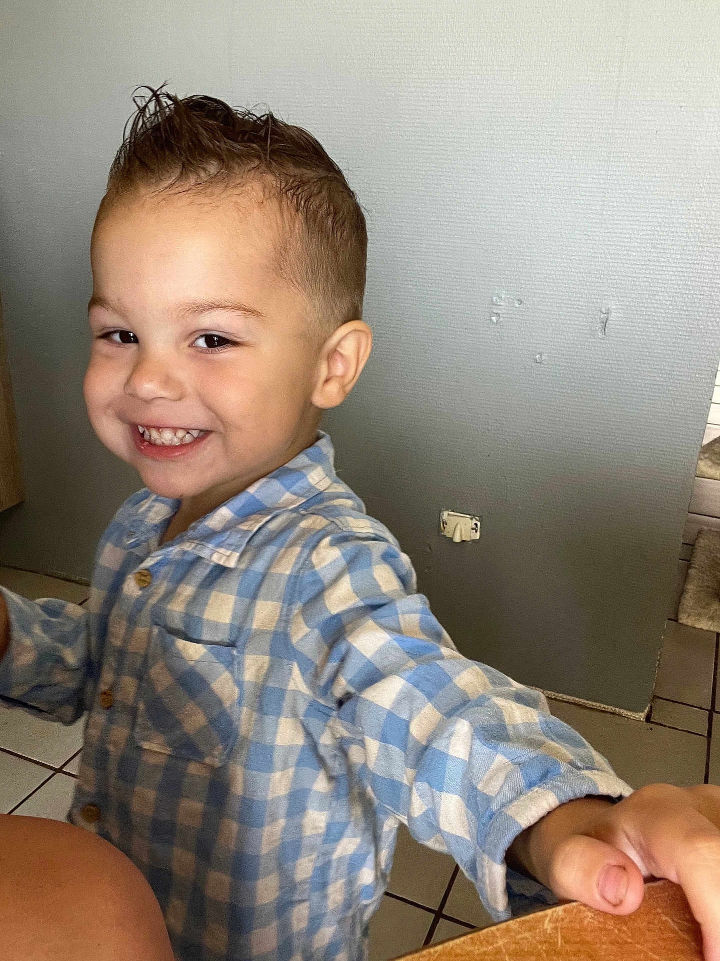 Hugo a rejoint le concours — aidez-le/la à gagner de superbes lots ! child, smiling, happy, indoor, blue_checkered_shirt, short_hair, spiked_hair, tiled_floor, wall, hand, cute, portrait, boy, person, casual_clothing, cheerful, young, playful, candid, light