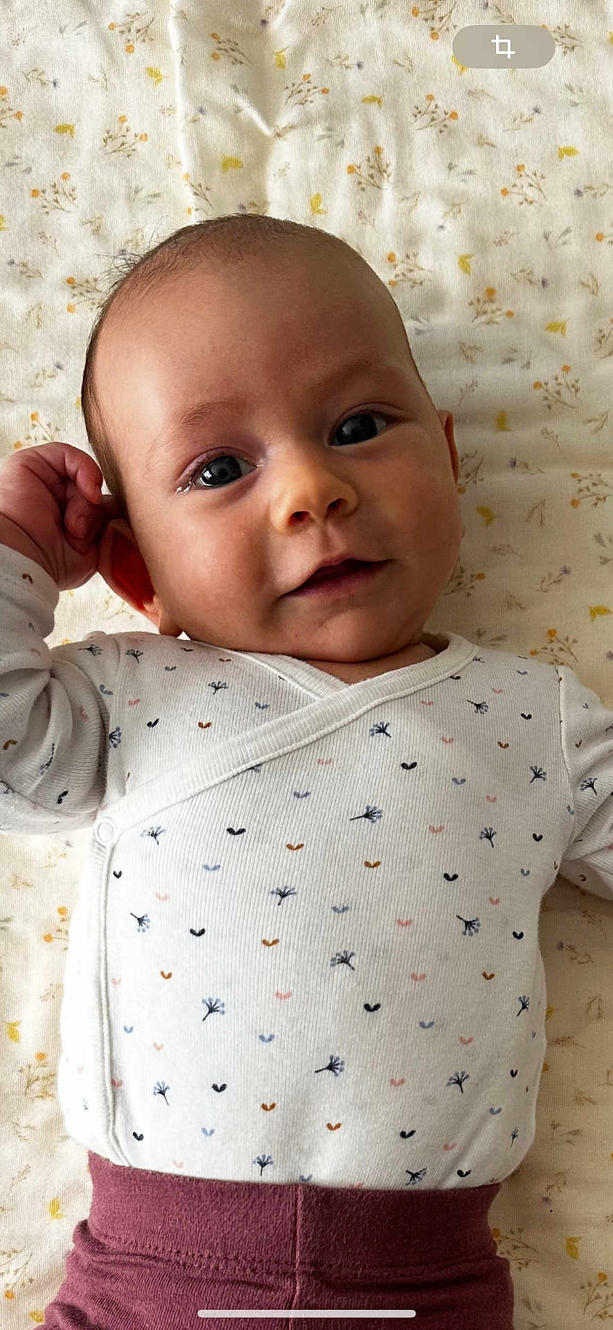 Ellie participe au concours pour gagner de l'argent avec cette photo : baby, infant, face, onesie, clothing, blanket, pattern, floral, smile, hand, lying_down, cute, child, skin, head, eyes, person, indoors, young, portrait