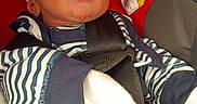 Nehemiah is registered to the contest to win money with this photo: baby, black, blue, car_seat, child, closeup, face, headwear, indoors, infant, mittens, newborn, peaceful, portrait, red, seatbelt, sleeping, striped_clothing, warning_label, white