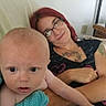 Dakota is registered to the contest to win money with this photo: baby, infant, adult, woman, portrait, indoors, sitting, couch, glasses, red_hair, smiling, curious, family, caregiver, tattoo, turquoise, polka_dot, clothing, home, close_up