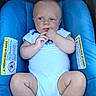 baby, infant, child, portrait, car_seat, blue, white_onesie, sitting, lying_down, wide_eyes, hand_in_mouth, bald, indoor, close_up, photograph, safety_label, warning_sign, seated, adorable, vehicle_interior