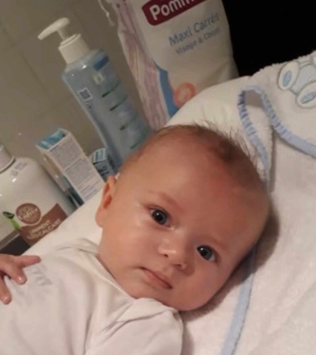 Andrews Dujardin participe au concours pour gagner de l'argent avec cette photo : baby, infant, face, eyes, towel, white_clothing, skin, hand, baby_care_products, bottle, pump, background, indoor, closeup, portrait, young, cute, child, laying, soft
