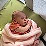 baby, newborn, sleeping, blanket, pink_blanket, crib, mesh_sides, green_mattress, infant, peaceful, cozy, wrapped, cute, small, child, indoors, soft_texture, resting, person, toddler