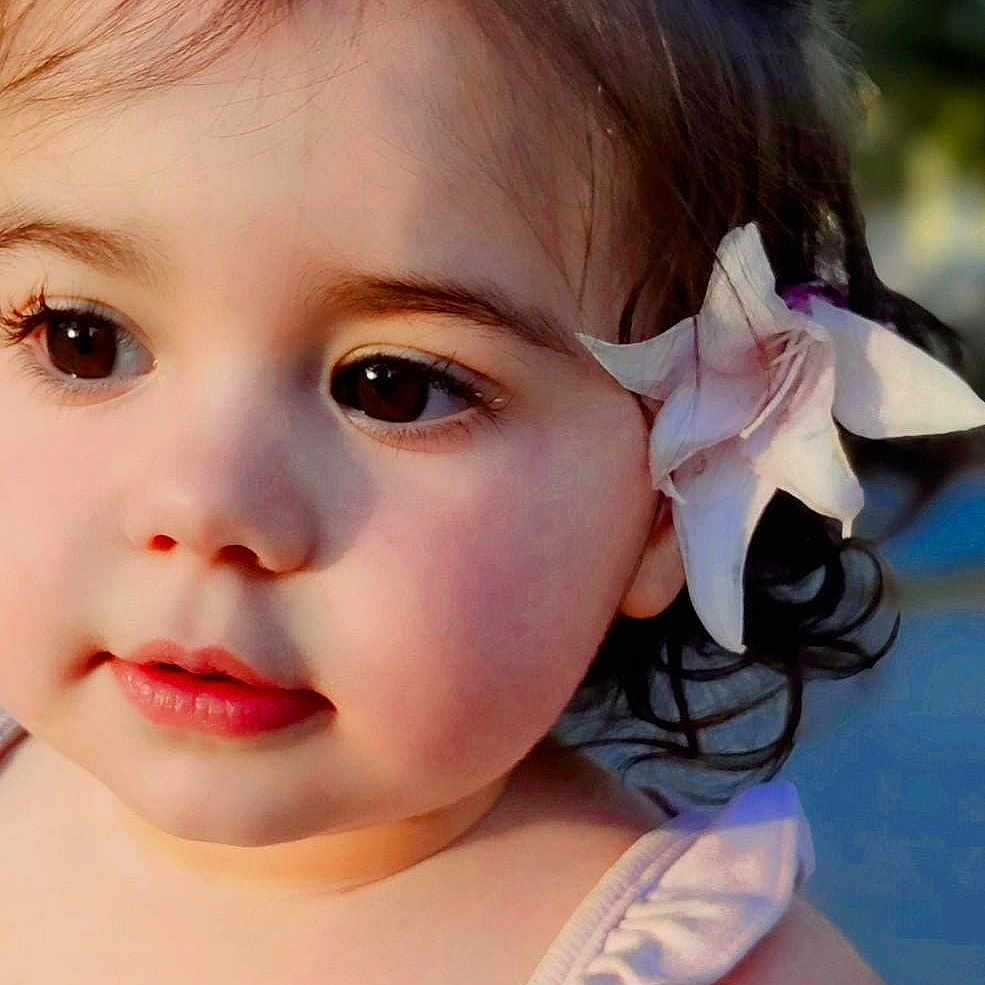 Millessa is registered to the contest to win money with this photo: baby, child, closeup, curiosity, cute, eyelashes, face, flower, hair, innocence, outdoor, person, portrait, shoulder, skin, soft_light, summer, tank_top, toddler, young_child
