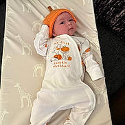 Kylo joined the competition — help win amazing prizes! baby, infant, giraffe_pattern, cushion, pumpkin_hat, onesie, cute, child, lying_down, indoors, soft_lighting, white_clothing, orange_hat, patterned_fabric, portrait, small_child, looking_up, baby_clothes, comfortable, resting