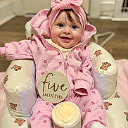 Romi joined the competition — help win amazing prizes! baby, infant, pink_clothing, headband, smiling, sitting, baby_seat, teddy_bear_pattern, indoor, floor, cute, child, portrait, happy, young, cozy, onesie, sock, five_months, wooden_sign