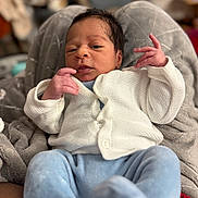 Noah a rejoint le concours — aidez-le/la à gagner de superbes lots ! baby, blanket, blue_pants, candid, closeup, cozy, curious_expression, face, hands, indoor, infant, knitwear, newborn, person, portrait, relaxed, seated, soft_fabric, warm, white_sweater