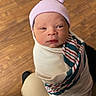 Eithan Gabriel is registered to the contest to win money with this photo: newborn, baby, infant, child, portrait, wrapped, swaddle, hat, striped_hat, pink, awake, face, eyes, indoors, wooden_floor, caretaker, lap, cozy, photography, safe