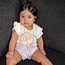 toddler, child, baby, sitting, couch, white_shirt, purple_shorts, purple_socks, white_sneakers, necklace, dark_hair, indoors, portrait, cute, expression, comfortable, textile, furniture, casual_clothing, young_child