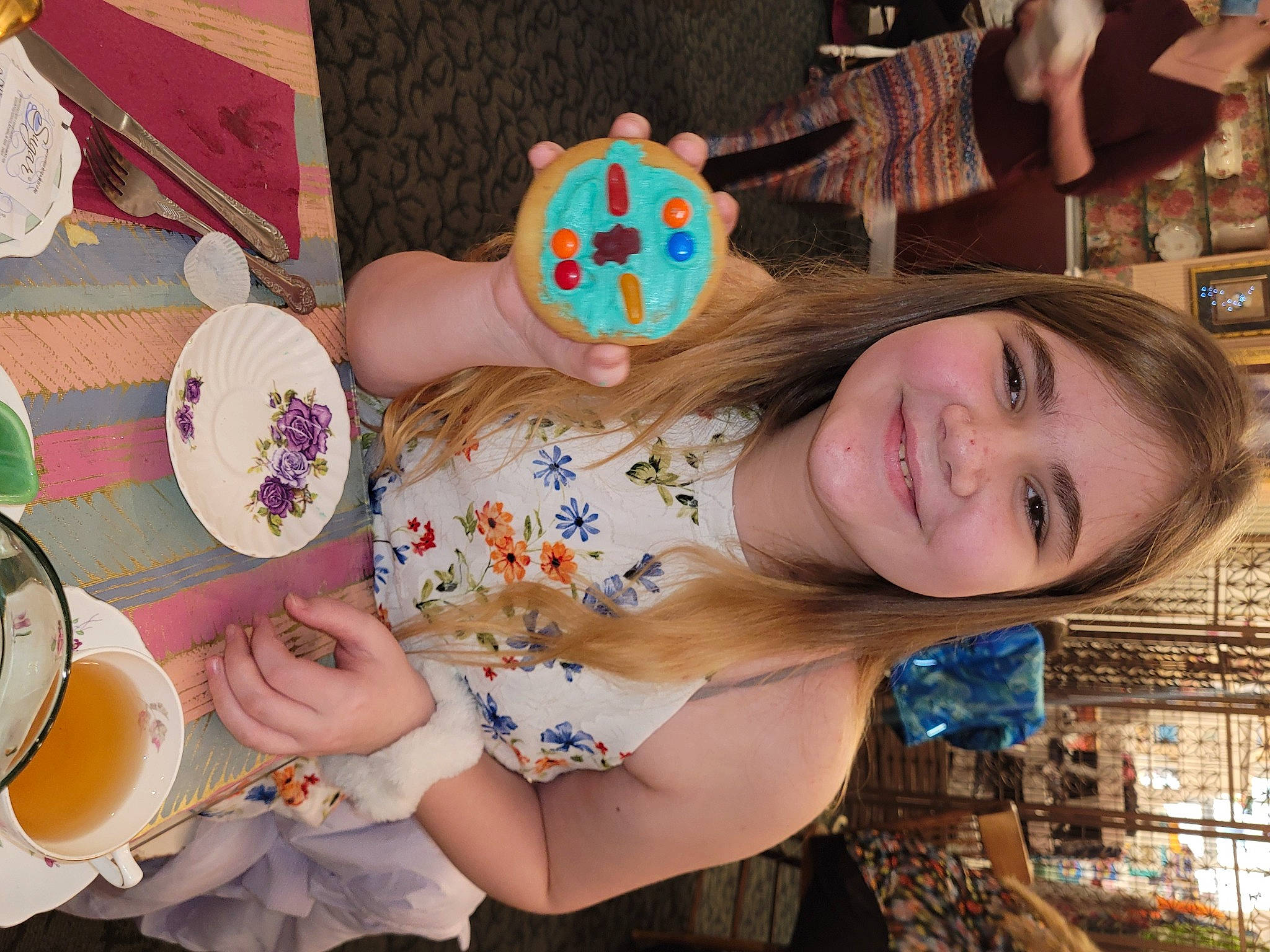 Abby is registered to the contest to win money with this photo: child, coffee_cup, cup, dishware, drinkware, food, fun, happy, human, joy, mouth, person, plate, porcelain, serveware, smile, sweetness, table, tableware, teacup