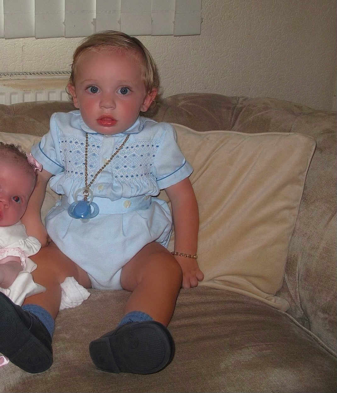 Wallace-Raymond joined the competition — help win amazing prizes! toddler, child, baby, doll, pacifier, blue_outfit, blue_eyes, couch, indoor, sitting, black_shoes, bracelet, pillow, wall, radiator, curtain, face, person, toy, furniture