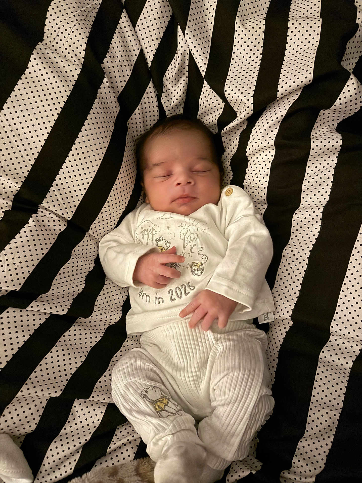 Ellias is registered to the contest to win money with this photo: baby, newborn, sleeping, white_clothing, striped_blanket, polka_dot, infant, cute, peaceful, soft, child, portrait, resting, small_hands, soft_texture, indoors, cozy, lying_down, young_child, infant_clothes