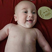Zachary joined the competition — help win amazing prizes! baby, infant, child, smiling, happy, portrait, close_up, lying_down, bare_chested, red_blanket, milestone_sign, round_sign, celebration, indoor, soft_lighting, face, eyes, mouth, family_photo, adorable