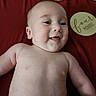 baby, infant, child, smiling, happy, portrait, close_up, lying_down, bare_chested, red_blanket, milestone_sign, round_sign, celebration, indoor, soft_lighting, face, eyes, mouth, family_photo, adorable