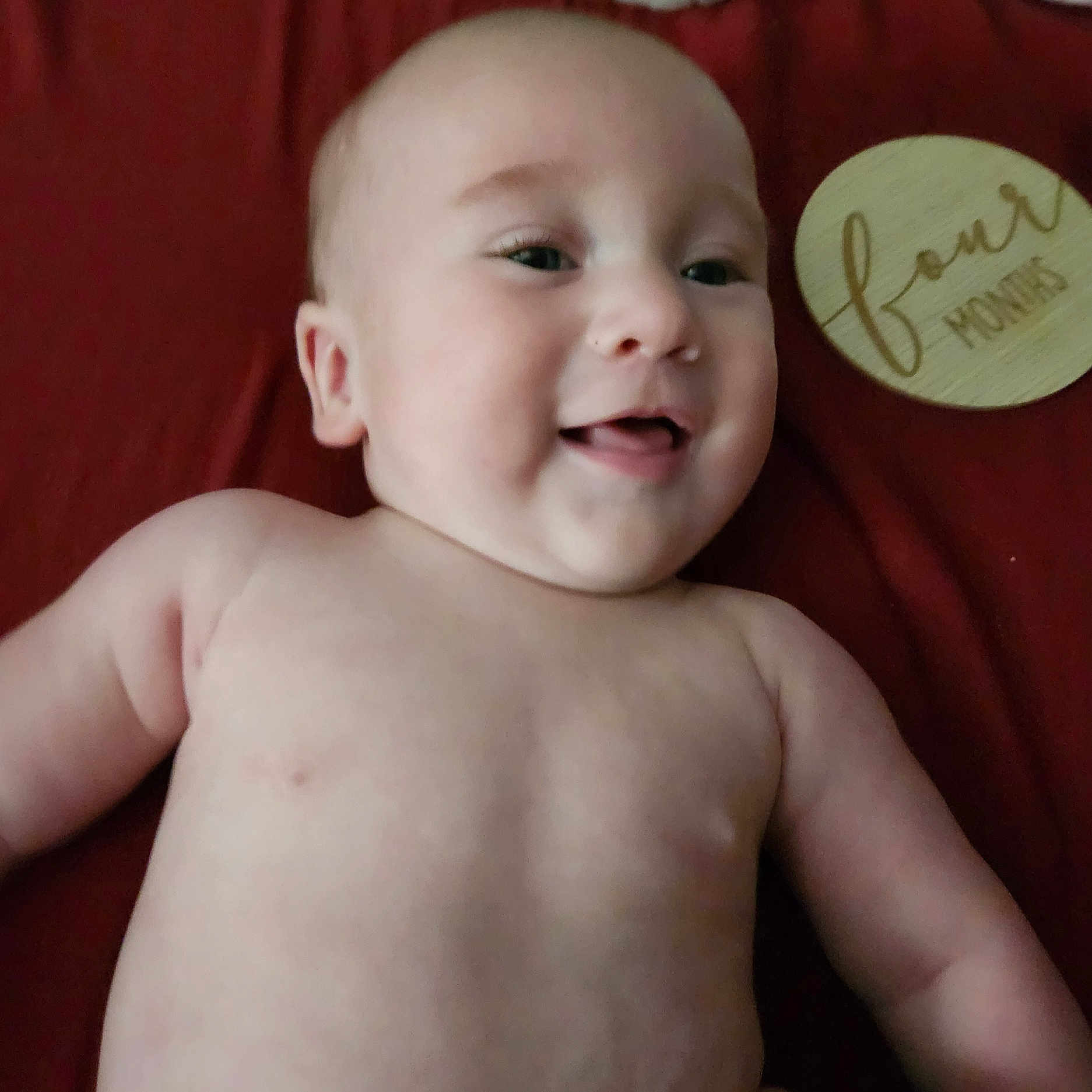 Zachary joined the competition — help win amazing prizes! baby, infant, child, smiling, happy, portrait, close_up, lying_down, bare_chested, red_blanket, milestone_sign, round_sign, celebration, indoor, soft_lighting, face, eyes, mouth, family_photo, adorable