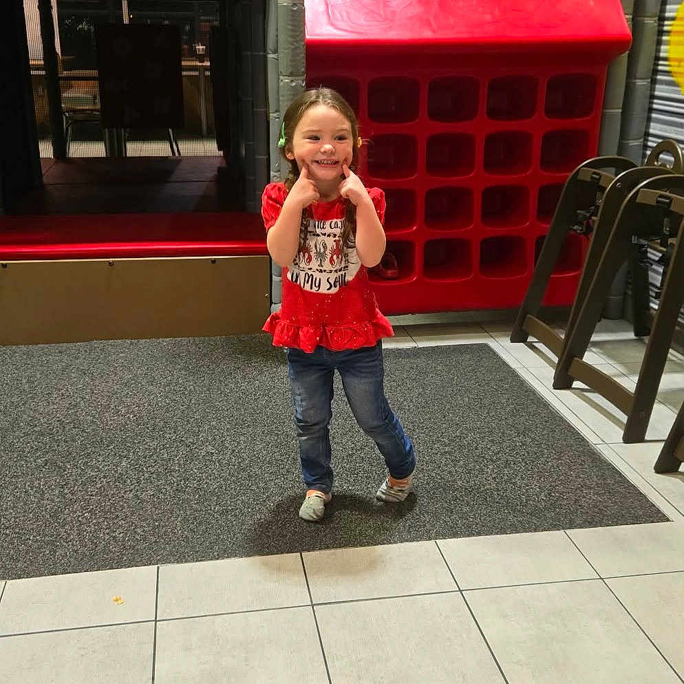 Allayna joined the competition — help win amazing prizes! casual_clothing, child, childhood, colorful, cute, floor_tiles, fun, girl, happy, indoor, jeans, joyful, netting, play_area, play_equipment, playground, posing, red_shirt, smiling, young