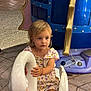 toddler, child, blonde_hair, swan_ride, playground, floral_dress, curious, hands, white_swan, ride, amusement_park, floor_tiles, indoor, play_area, young_child, toy, seat, person, cute, portrait
