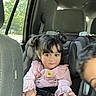 Sally joined the competition — help win amazing prizes! child, toddler, car, car_seat, sitting, pink_clothing, pigtails, smiling, portrait, indoor, vehicle, passenger, seatbelt, safety, window, sunlight, sock, cup_holder, family, photobomb