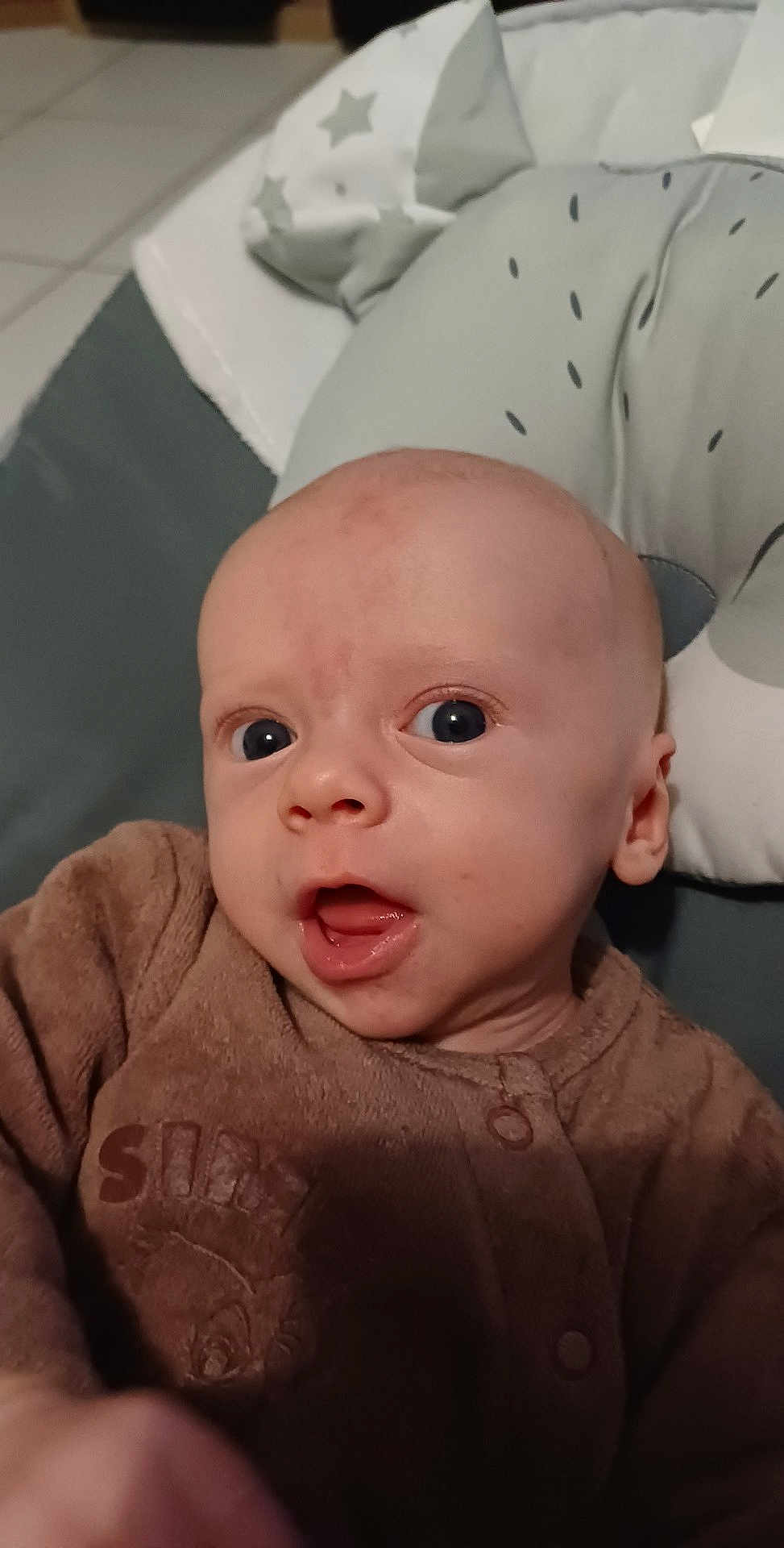 Noah a rejoint le concours — aidez-le/la à gagner de superbes lots ! baby, infant, face, eyes, mouth, clothing, onesie, cushion, soft, expression, skin, head, ear, indoors, child, young, person, portrait, cute, babywear