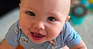 Jeffery is registered to the contest to win money with this photo: baby, blue_onesie, child, closeup, cute, eyes, face, hands, happy, head, human, indoor, infant, looking_up, mouth, person, photography, playful, skin, smiling