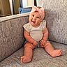 baby, child, smile, headband, pink_bow, couch, gray_couch, sitting, happy, indoors, cute, infant, shorts, white_shirt, plush_furniture, portrait, chubby_arms, chubby_legs, home, cozy
