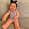 baby, child, smile, headband, bow, floral_outfit, couch, gray_couch, sitting, happy, indoors, person, infant, cute, plump_arms, plump_legs, skin, hand, foot, portrait