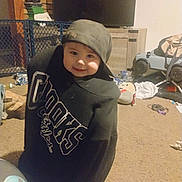 Loki joined the competition — help win amazing prizes! toddler, child, hoodie, cap, smile, indoor, carpet, toy, footwear, furniture, television, cabinet, playpen, stuffed_toy, keys, messy_room, person, clothing, barefoot, home