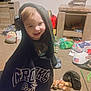 Loki is registered to the contest to win money with this photo: child, toddler, hoodie, smiling, indoor, carpet, toy, stuffed_animal, helmet, furniture, cabinet, plastic_bottle, floor, room, playful, clothing, face, person, mess, home