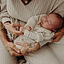 baby, newborn, infant, tattoos, hands, knitwear, sleeping, person, couch, arm, closeup, cozy, soft, neutral_colors, indoor, resting, peaceful, skin, portrait, holding