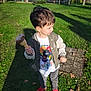 child, boy, ice_cream, ice_cream_cone, park, grass, red_shoes, jacket, t_shirt, playground, sunny, shadow, smile, walking, snack, toddler, short_hair, outdoor, casual_clothing, daytime
