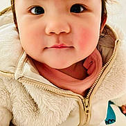 Gabrielle is registered to the contest to win money with this photo: toddler, child, face, portrait, cute, baby, clothing, jacket, fuzzy, zipper, pants, star_pattern, indoor, sitting, curious, rosy_cheeks, young_child, person, closeup, warm_clothes