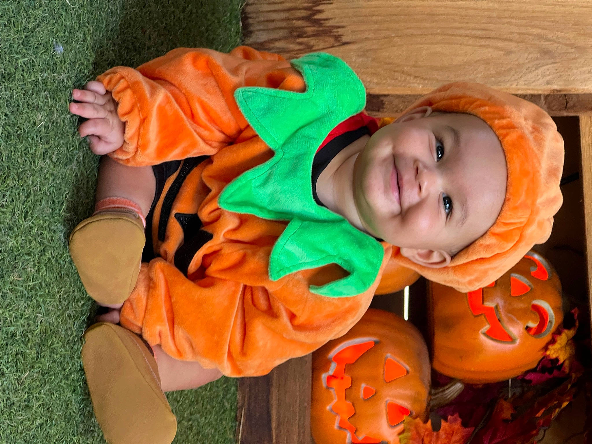 Amir is registered to the contest to win money with this photo: baby_toddler_clothing, calabaza, child, cucurbita, eye, facial_expression, fun, grass, happy, head, headwear, human_body, joy, mouth, orange, outerwear, person, plant, pumpkin, sitting