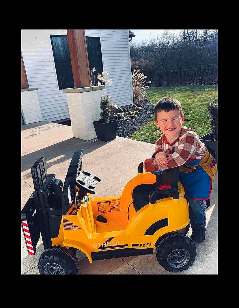 Jason is registered to the contest to win money with this photo: auto_part, automotive_design, automotive_exterior, automotive_lighting, automotive_tire, automotive_wheel_system, fender, happy, joy, motor_vehicle, person, plant, riding_toy, rim, scooter, smile, t_shirt, tire, toddler, vehicle