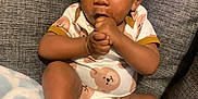 Ace joined the competition — help win amazing prizes! baby, infant, child, onesie, bear_pattern, hand_in_mouth, socks, blanket, couch, seated, curious, soft_lighting, indoors, cute, portrait, cozy, young_child, skin, expression, comfortable