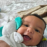 Miles is registered to the contest to win money with this photo: baby, smiling, face, plush_toy, bed, blanket, happy, child, cuddling, closeup, infant, indoors, person, cute, soft_toy, comfort, expression, portrait, skin, head